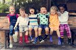 Kids laughing while wearing rainboots and sitting on a bench
